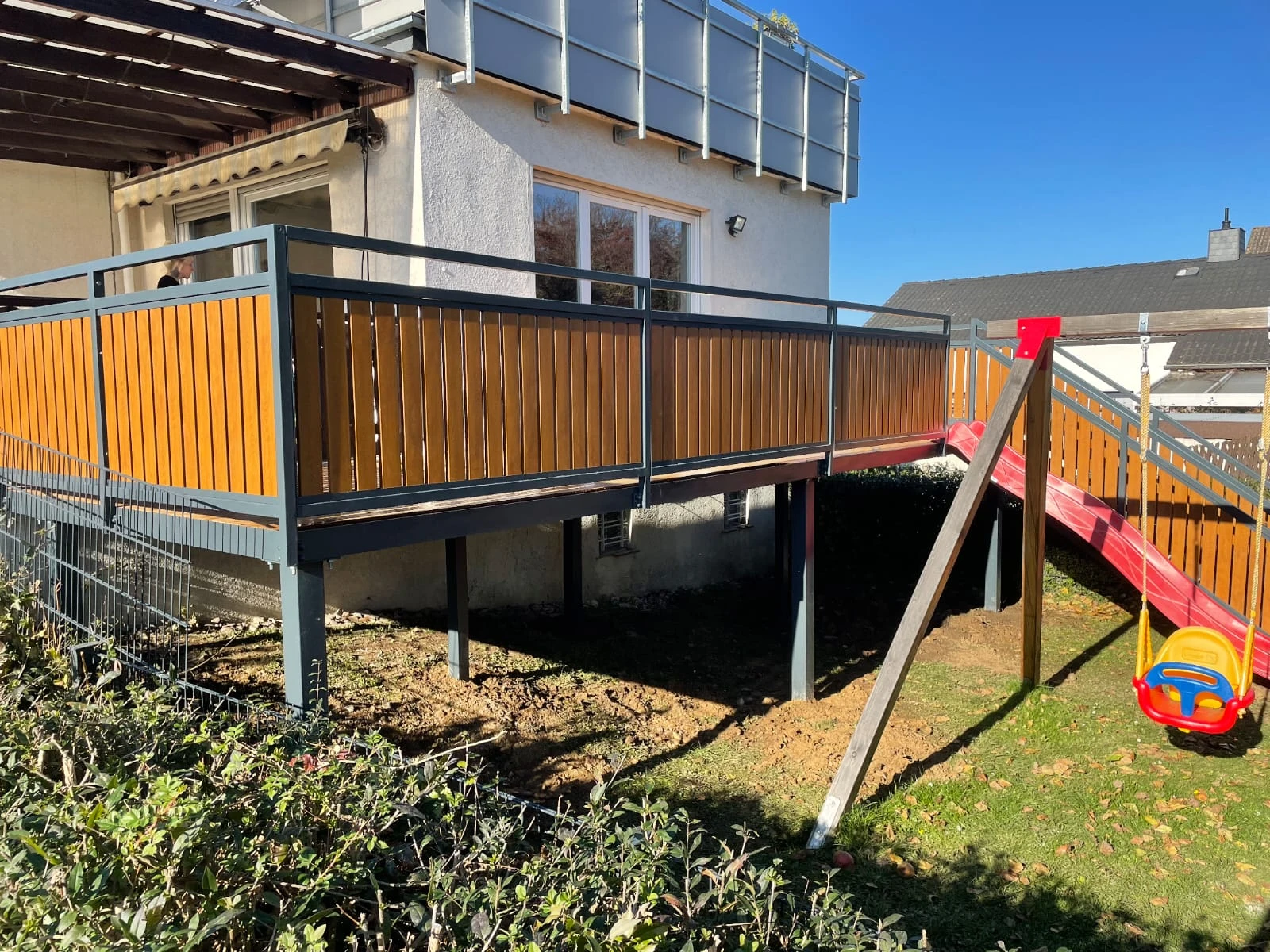 Erhöhtes Terrassengeländer aus Stahl mit Holzelementen an Einfamilienhaus
