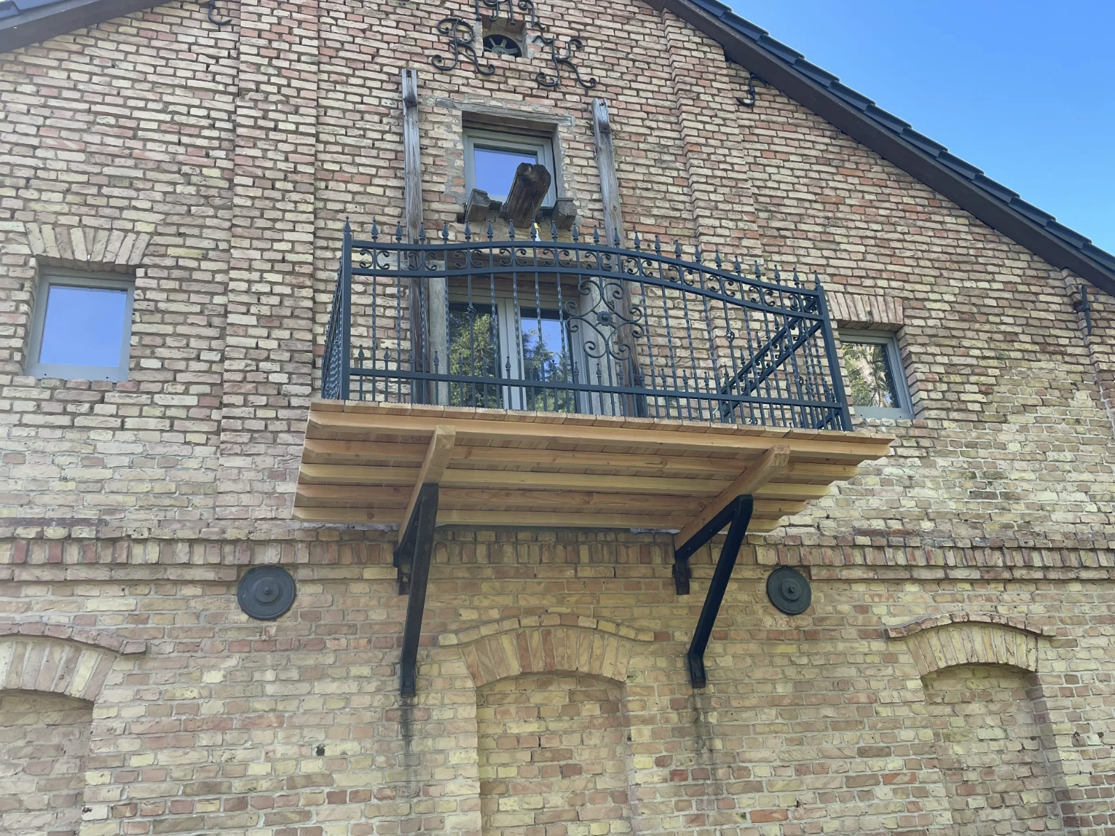 Französische balkone mit schmiedeeisernem Geländer und Holzpodest an Backsteinfassade