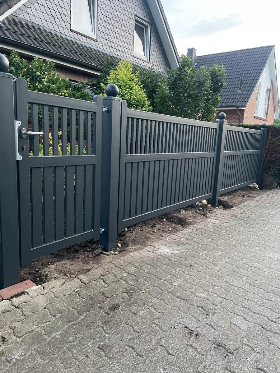 Aluminium zäune mit Eingangstor und vertikalen Lamellen vor modernem Einfamilienhaus