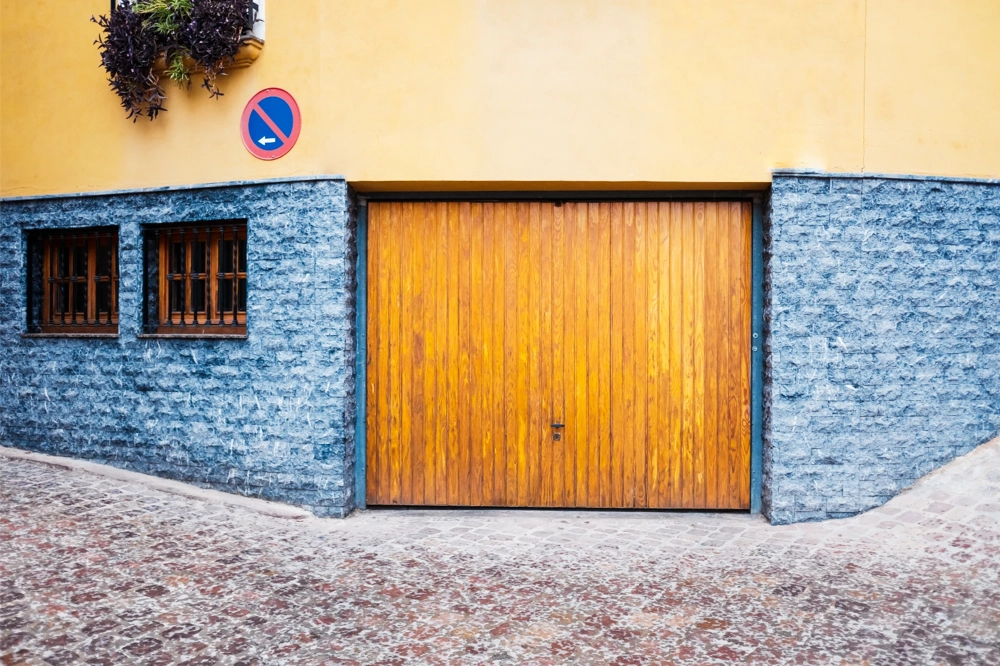 Holz-Garagentore in moderner Steinfassade mit Fenstern und Pflasterweg